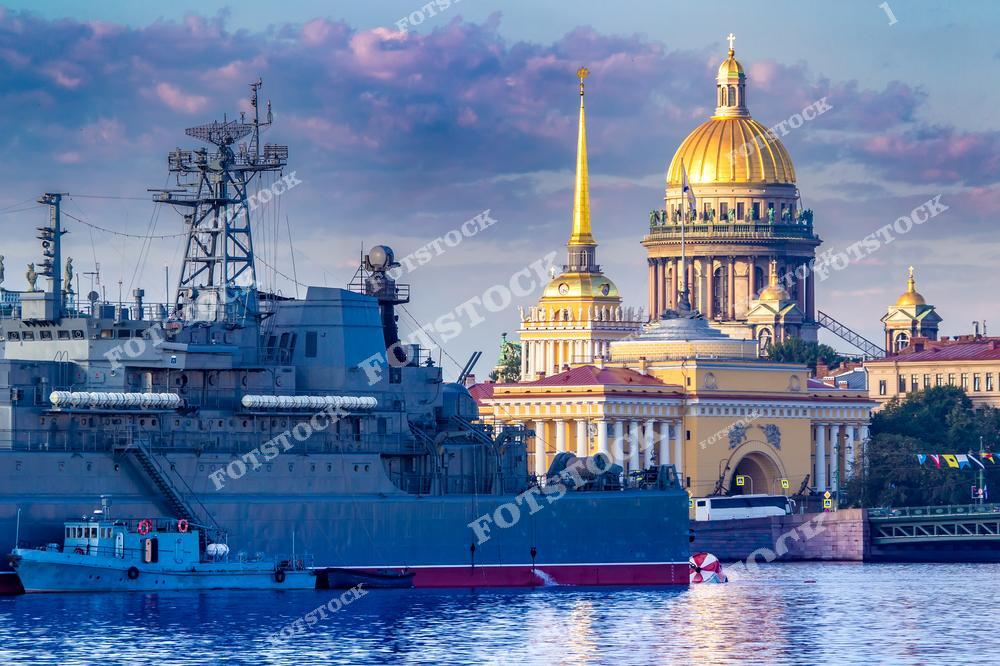 На фотографии изображен военный корабль у набережной Санкт-Петербурга, на фоне которого возвышается Исаакиевский собор. Золотой купол и шпиль собора придают величественность этому виду.